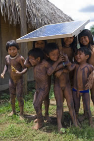 Children with body paint playing under the shade of the solar panel, used for the radio (communications). Ngoiwere Village, Mato Grosso State, Brazil. Photograph: Sue Cunningham Photographic