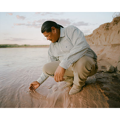 Nolan Stevens dips his hand into the Little Colorado River © Elliot Ross